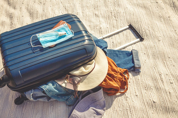A packed suitcase for a quick getaway or staycation with mask and sanitiser ©Shyntartanya/Shutterstock.com