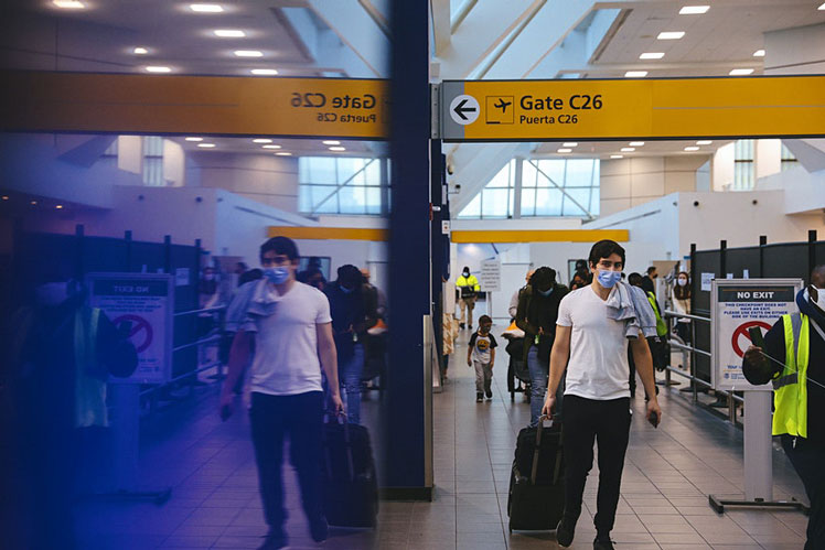 Travelers wearing protective masks walk through LaGuardia Airport (LGA) in New York, US on Christmas Eve © Bloomberg via Getty Images