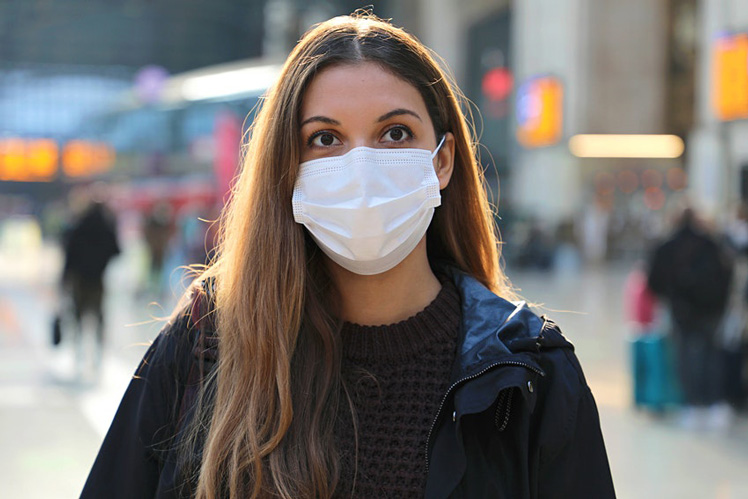 Travelers wearing protective masks walk through LaGuardia Airport (LGA) in New York, US on Christmas Eve &copy; Bloomberg via Getty Images