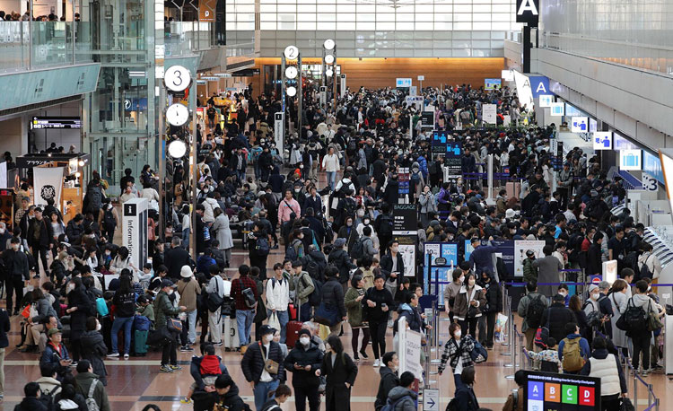 Travelers crowd the check-in area at terminal 2 at Tokyo's Haneda Airport on January 3, 2024. - Stringer/JIJI Press/AFP/Getty Images