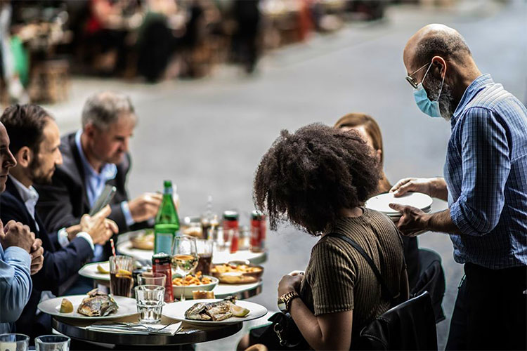 A waiter serves customers at a terrace of a restaurant in Paris as cafes and restaurants are allowed to serve customers inside, as well as on terraces. &copy; Martin BUREAU/AFP via Getty Images