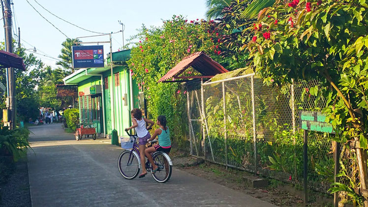 Two girls pedal down the main road of Tortuguero ©Bailey Johnson/Lonely Planet