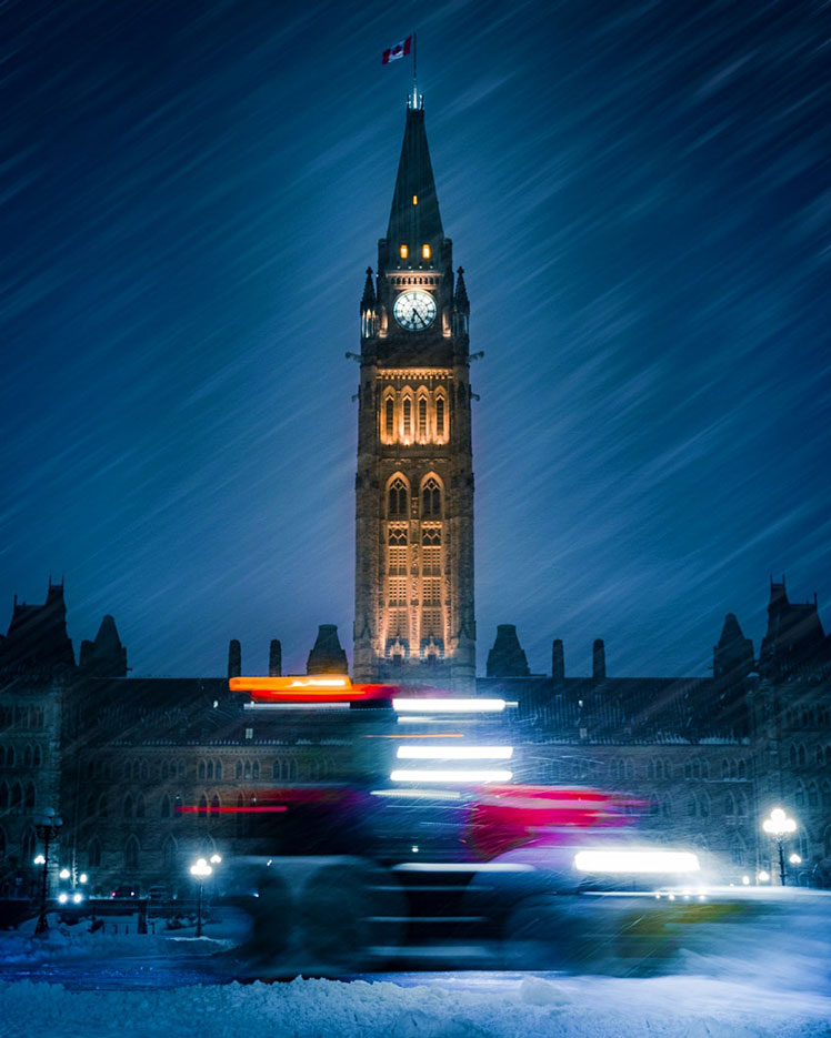 The Canadian Parliament building is illumnated against softly falling snow in winter © Bist / Shutterstock