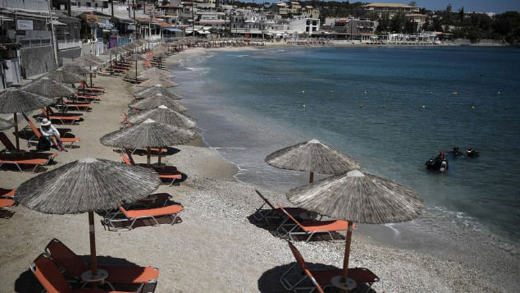 Umbrellas on a beach at Agia Pelagia on the Greek island of Crete were ready for tourists on May 14, 2021. Greece has eased restrictions for some international visitors while EU-wide policies are still being finalized. LOUISA GOULIAMAKI/AFP/AFP via Getty Images